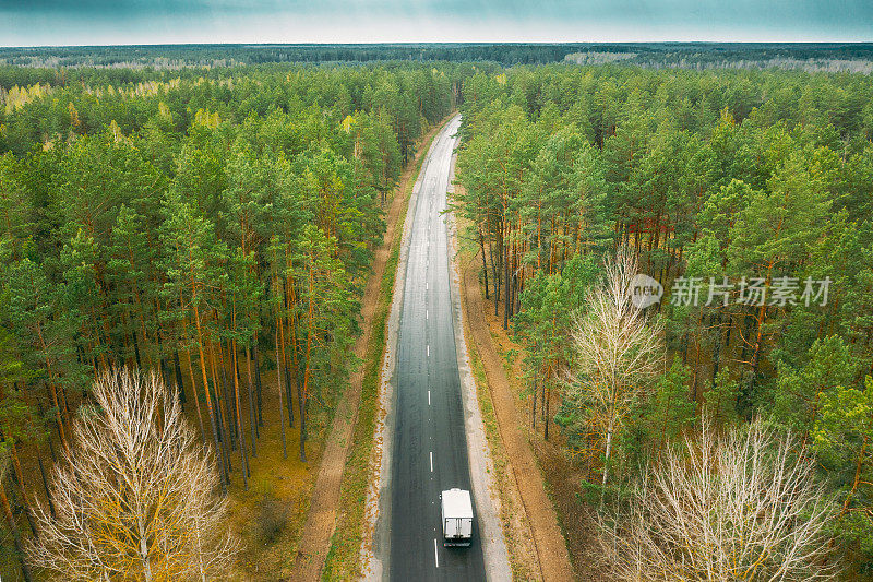 公路鸟瞰图穿过春天的森林景观。Top View Of Truck Tractor Unit原动机牵引单元在高速公路上运动。商业运输，卡车运输行业